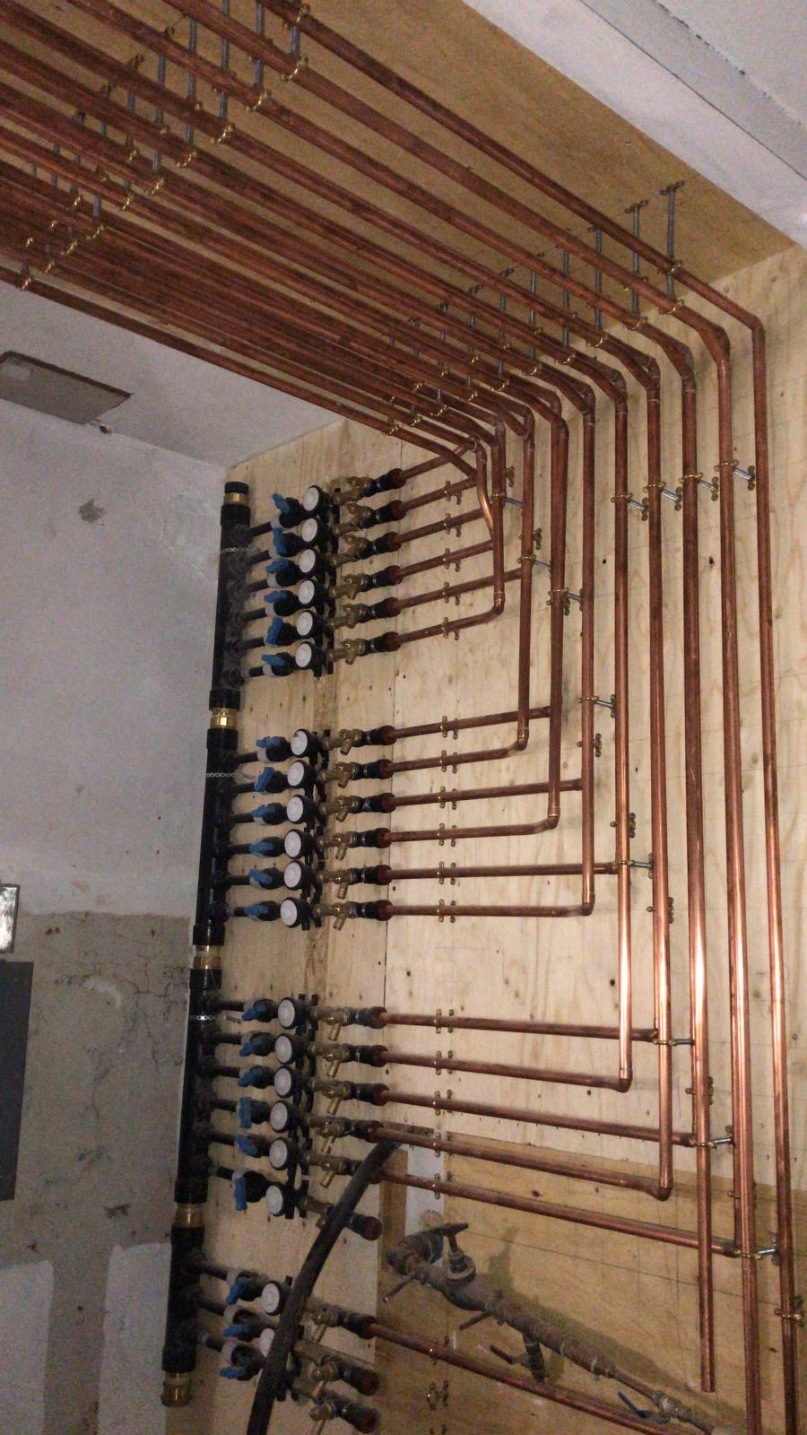 Multiple neatly arranged copper pipe runs and valve connections